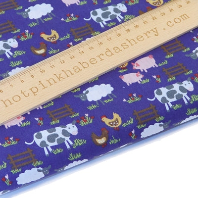Playful, children's farmyard animal print with cows, sheep, chickens & pigs, fences and flowers in navy blue on polycotton fabric