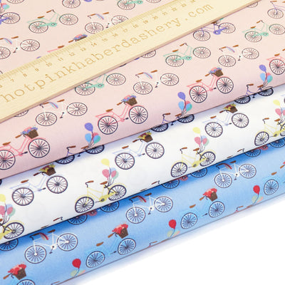 Fun and colourful bicycles and balloons print 100% cotton poplin fabric in white, pink and blue.