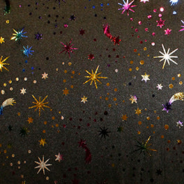 Swatch of fun, shimmery rainbow foil print with fireworks and shooting stars night sky multi colour fabric