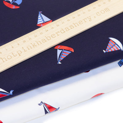 Fun, nautical sailing boats in shiny foil with stripes and anchors on jersey fabric by John Louden in white and navy