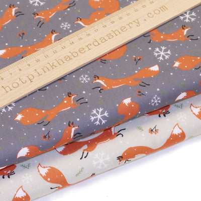 Playful Christmas winter foxes with festive snowflakes on polycotton fabric in grey and cream