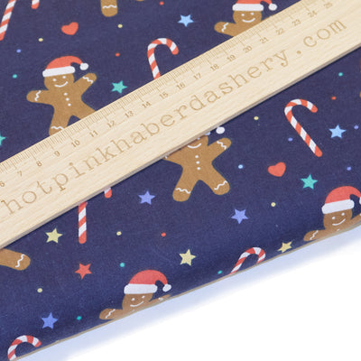 Festive gingerbread and Christmas candy canes with stars and Santa hats on polycotton fabric in navy blue